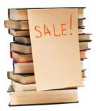 Photo of a stack of books with a SALE! sign attached.