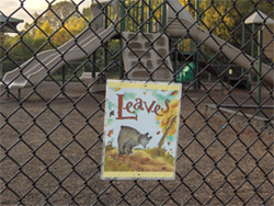 Photo of park with a page of a book attached to the fence.