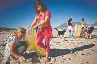 Photo of children picking up trash on the beach.