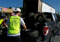 Photo of an Asheville Greenworks volunteer unloading tires from a truck.