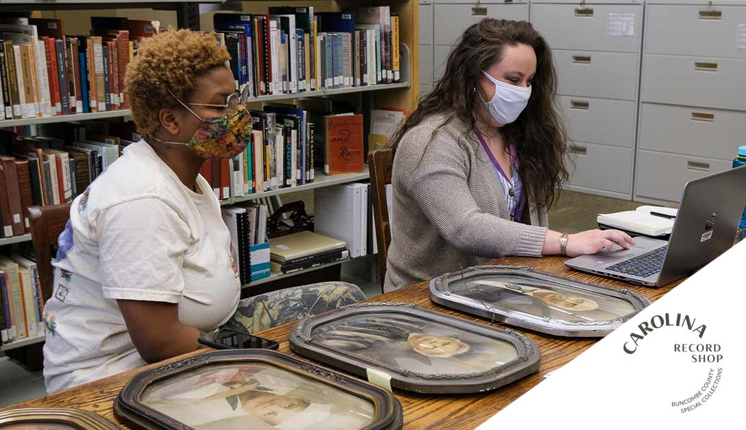 Two women look at historic photos in a library. 
