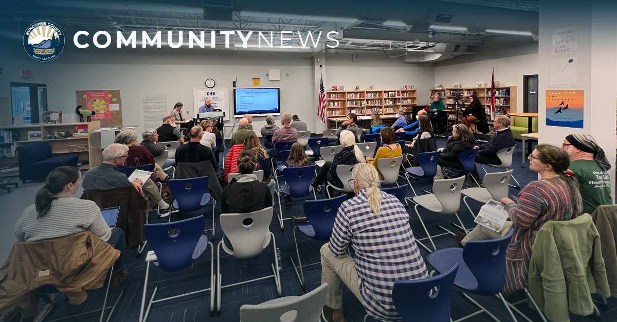 a crowd sits at a public meeting