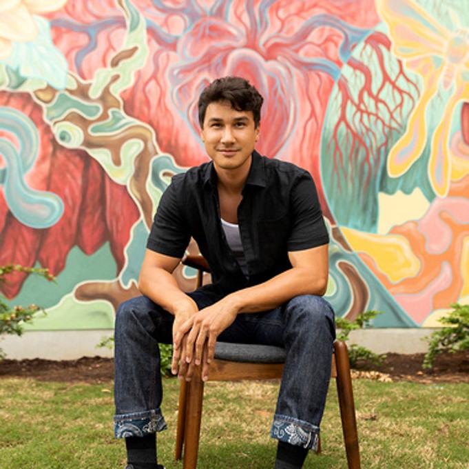 A person sitting in a chair in front of a wall with graffiti