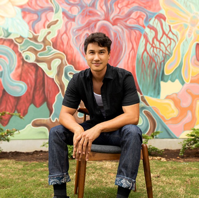 A person sitting in a chair in front of a wall with graffiti 