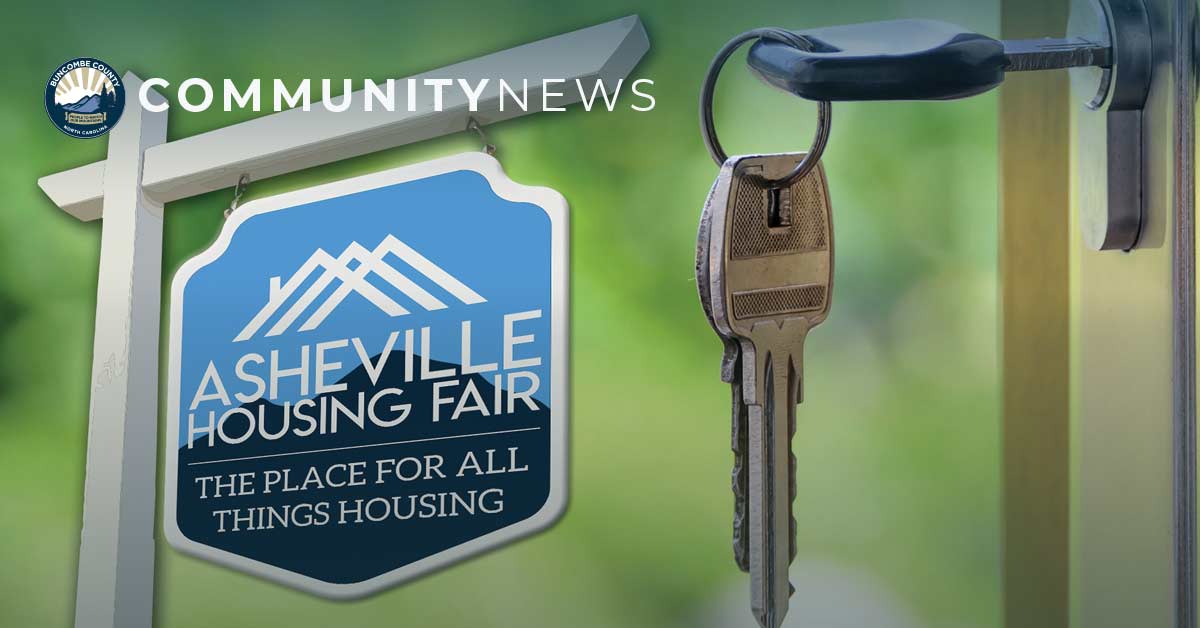 a sign in the foreground says Asheville housing fair